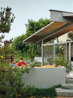 A Midcentury Home Keeps the History Alive - Photo 4 of 10 - Loehnen and Fissmer relax on a bench outfitted with orange pillows by Sunbrella on the deck outside their living room.