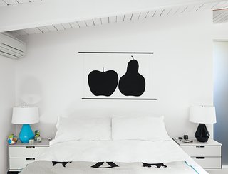 A Midcentury Home Keeps the History Alive - Photo 7 of 10 - A print of Enzo Mari’s La Mela e La Pera for Danese Milano hangs in the master bedroom. Delta lamps by Robert Abbey sit atop bedside tables from Rams’s 606 shelving system for Vitsœ.