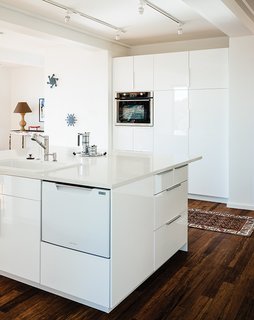 The kitchen, which sits at the center of the house, features recycled glass countertops, Ikea cabinets, and carbonized bamboo floors. "We had Thanksgiving dinner there," says the daughter. "There’s no sense of the house as small. It feels like a house."