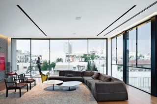Modern High-Rise Town House in Tel Aviv - Photo 3 of 7 - The living room features stunning views of the city, a Bend sofa and Phoenix coffee tables, both by Patricia Urquiola for B&B Italia and Moroso, respectively, and two Gray armchairs by Piero Lissoni for Living Divani.