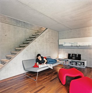 At the bottom of the stairs is a second living space that includes a fireplace. The couple couldn't find a television that didn't clutter the cool minmalism so they prefer to use a projector to watch movies. The sofa was designed by Barber-Osgerby for Cappellini, and the Djinn chair is by Olivier Morgue.