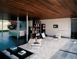 The Mariscals' daughter, Olivia, whiles away the afternoon in the breezy living room. She sits on a sheepskin-covered Flag Halyard chair by Danish master Hans Wegner.