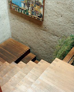Rail-free stairs are unnerving for a first-time visitor, but they amplify the home's free-flowing sense of space and structure. The stairs were built inside one of the six concrete towers, and they lead from the central living space to the front door. The experience of moving from the enclosed stairway into the expansive open family area is dramatic.