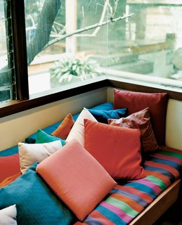 The exposed wood and raw concrete throughout the house are offset by bold colors, chosen by Shelly and the children. The house's warm hues can clearly be seen in this window seat in Ray's office.