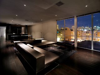 The penthouse living room is furnished with Ile Club by Piero Lissoni for Living Divani. The Metropolitan Riverside Park City Lights rug is by Merida.