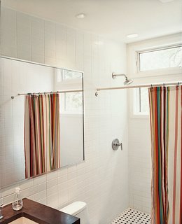 A brightly striped shower curtain lends bright punctuation to an otherwise austere bathroom.