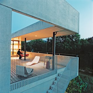 The couple do their outdoor lolling on Willy Guhl's concrete Loop chair (near grating) and Superieur's Divan lounge (near the table), both Swiss products.