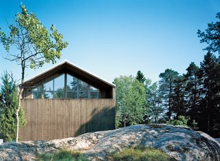 The pitched facade has a sculptural play of spruce siding and triple-glazed windows that reflect the surrounding treetops.