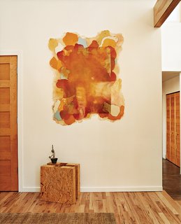 Walking in the front door it's hard to miss the square chunk of compressed-straw paneling—a building material-cum-sculpture that allows visitors to see what the house is made from. Kahn's paintings hang throughout the house, and several of the rugs are her original designs.