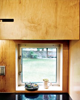 Geometric notches in the kitchen cabinetry are simple and cost-effective substitutes for metal cabinet pulls—they also provide visual interest in an otherwise unadorned space.