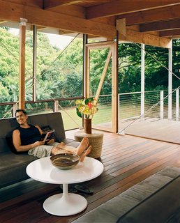 The living area, with its pair of sleeper sofas and Ikea coffee table, doubles as the guest bedroom when not being enjoyed by Kurokawa. It is framed by floor-to-ceiling screen walls. Details of the home's construction, such as the simple cuff that attaches post to beam, are purposefully left exposed.