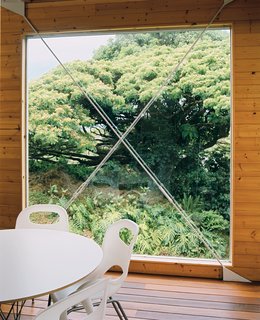 A huge window next to the dining area is punctuated by a steel X form.