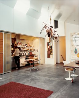 A dedicated cyclist, Baker suspends his bikes using a rope-and-pulley system. Paco Prieto of Pacassa Studios designed the small table on which the pumpkin rests; the dining table was designed by Baker and fabricated by Thomas Jameson. The painting is by local artist Rex Ray.