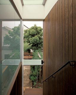 The sheltered stairway, bordered on one side by glass and on the other by ipe planks, creates a gentle descent from the garage to the garden.