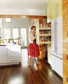 The kitchen links the new and old parts of the house; fittingly, its style is somewhere between traditional and modern. A kitchen wall makes room for a fridge and roll-out shelving.