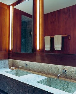 Humble materials are used to good effect throughout the apartment. The bathroom contains ordinary rope lights concealed above the sinks. The tumbled slate mosaic tiles are by Artistic tile. All the wooden bathroom accessories were purchased from Ikea.