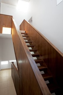 Despite its dark and boxy exterior, the house's interior is bright, naturally lit, and spacious. Adjaye, a master of the well-placed window, is in top form here. The staircase ascends toward sunlight.
