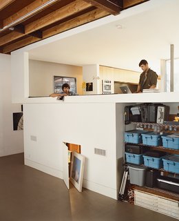 Light Box - Photo 6 of 7 - The couple’s living room (which includes a flat-screen TV) overlooks Tad Beck’s studio; art supplies are stored in niches that are invisible from the living space above. A hallway along the edge of the building provides an alternate route to the front door.