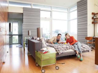 Top Notch - Photo 2 of 4 - Koshkarian and DiFrancesco lounge on their Poliform bed with their daughter, Zia. The large windows annex an outdoor patio, which extends the already light-filled space into the outdoors.