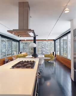 Fully enclosed by glass, Hiller’s kitchen and living room give the feeling of being in a tree house.