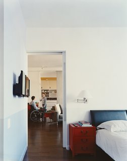 Behind the living room’s foam partition, and accented with orange paint, a storage wall includes a Murphy bed for guests.