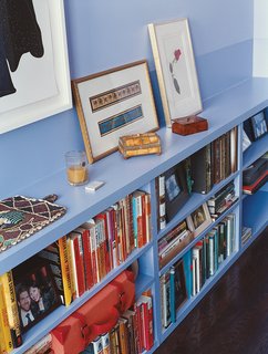 The bedroom is painted white with one blue wall and built-in shelving. Wood floors, largely rugless, are luminous and wheelchair friendly.