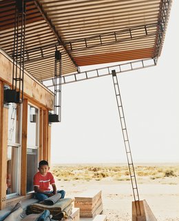 Nicholas sits in the shade of the roof; students cut and hand-welded thousands of reclaimed rebar pieces into a complex grid that would support four bi-level <br><br>corrugated-steel roof panels.