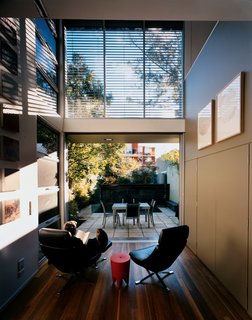 Wansbrough relaxes in the living room, a serene area with a bank of windows and an arrangement of Lezlie Tilley’s paintings inspired by the Australian bush.