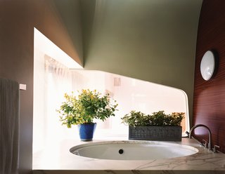 The window beside the tub in the master bathroom peers over the living space below and echoes the shiplike quality of the pod, which also contains the master bedroom. Lights reminiscent of portholes and mahogany walls deepen the feeling of being on an ocean cruise.