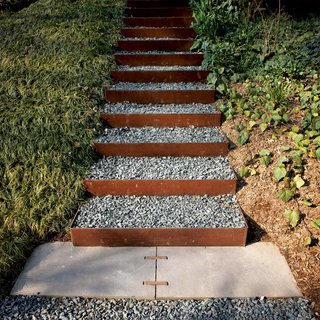 This House Tells the Time With an Oculus - Photo 5 of 6 - The stairs going up the knoll to the roof garden and to the house’s second-level entrance are made from Cor-Ten steel risers (which develop a rich, rusted patina) and filled with gravel in order to create a nonslip surface that drains well. Steel and steelwork by Virginia Industrial.