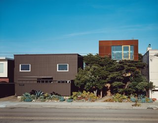 The original house (left) only gave two glimpses of the vast Pacific Ocean out of the west-facing windows—an unusual choice given the epic sweep and clear cachet of an uninterrupted ocean view. Aidlin Darling Design took a different tack with the new addition (right), using the cypress trees as a natural screen to shield the lower levels while opening the third floor to stunning views. The Cor-Ten steel cladding on the new house is designed to further redden and rust with the help of the obliging sea air.