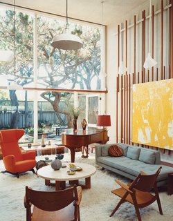 Born outfitted the living room of the original house with vertical slats on which to mount any manner of visual material. Artwork becomes easy to move around, but Lloyd-Butler likes the placement of a painting by Wayne Gonzales depicting Lee Harvey Oswald.