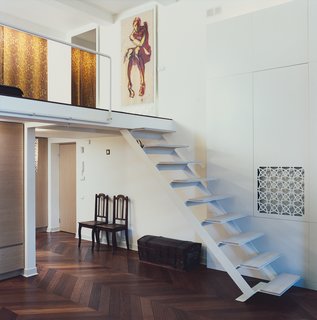 Palace Intrigue - Photo 5 of 13 - A couple items of antique furniture from Mikulionis’s family add to the flat’s feeling of history. A painting by Augustinas Liatukas, subject unknown, hangs at the entrance to the mezzanine bedroom above a custom lightbox featuring the ubiquitous CNC-cut geometric pattern.