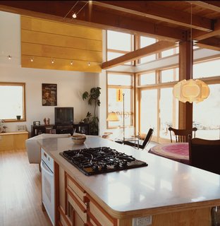 Light pours into the combined living, dining, and kitchen space at the front of the house. Antique furnishings are offset by the striking Pendant 169 lamp by Danish architect Poul Christiansen for Le Klint.