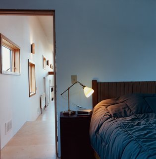 A hallway lined with windows provides a distinctive gateway to the bedroom.