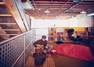 A House Grows in Brooklyn - Photo 5 of 5 - In the family room, Lucien gets an early start on his music career with his father’s help. The space, technically the third floor of the structure, overlooks the central living area below.