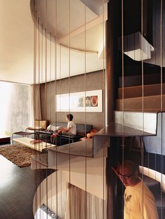 Yeo descends the spiral staircase that connects the public and private spaces while Ian relaxes on a pair of Cappellini Superlight 750 sofas designed by Barber Osgerby. The Gwapa lounge chair and ottoman in the corner were designed by Marcel Wanders.