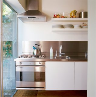 Garage Brand - Photo 2 of 8 - "You can stand in one space and reach everything," explains Colin of the precise kitchen layout with its custom-made stainless steel countertop, cantilevered cupboards, and integrated cooktop and oven. The cupboards’ shallow shelves were specially made to take up minimal space and to fit Muji storage jars.