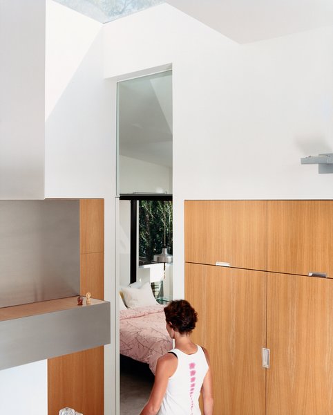 Venetian Vicissitude - Photo 1 of 9 - Dawn Farmer walks from the kitchen to a guest bedroom. The seven-foot-tall doorway lines up with the glass doors and cabinetry throughout the house—which is made of <br><br>13-layer multi-ply apple core with rift-oak veneer.