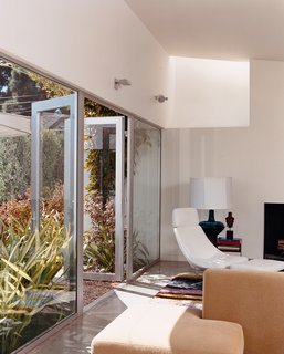 Seven-foot-high glass doors bring the garden, landscaped by Jay Griffith, into the living room. A skylight brings even more light into the white-walled room with polished-concrete floors. There is a splash of color in a custom rug designed by Dawn Farmer and made by Della Robbia, which also made the sofas.