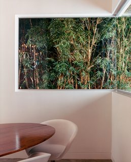 The dining room features a Tulip table by Eero Saarinen with a customized walnut top manufactured by Pietrarte and a contemporary chair by the Italian company Arper.