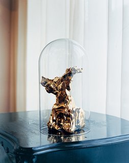 A gold-plated One Minute sculpture, under an antique glass dome.