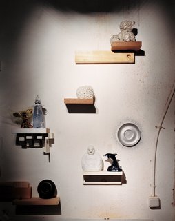 An installation of mismatched handmade shelves makes a display area for another enigmatic assortment of objects, including a Wanders Sponge vase (1997), made by soaking a real sponge in clay, which burns away when the piece is fired. The same technique was used on the silver-plated teddy bear above it. The dolphin and Buddha figures—perhaps a reminder of Wanders’s role in mainstreaming kitsch—illustrate the designer’s interest in ordinary, popular decorative objects.