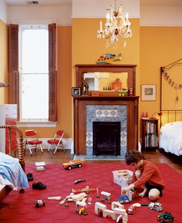 In the boys’ shared room, Jasper finds plenty of space to scatter toys. An original chandelier provides a reminder of the house’s past while muted orange walls plant it firmly in the present.