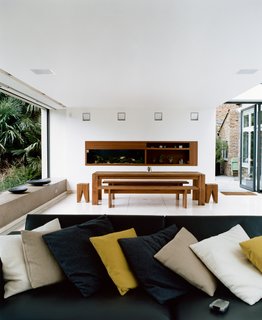 Victorian Secrets - Photo 5 of 10 - The new space was conceived as a blank canvas so that the decidedly nontraditional English garden—a large lawn bordered by exotic palms, bamboos, ferns, and other flamboyant foliage inspired by a recent holiday to Australia—could be the focal point. The minimalist dining table, benches, and stools are by e15.