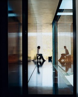 Xeros Effect - Photo 6 of 7 - The hallway leading to the sparsely furnished bedroom opens to a wall of glass, where the light reflects off the dark NAP board floors and walls. The lighter walls are thin-coat gypsum plaster with a beeswax coating.
