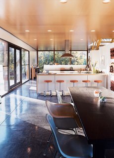 "It was a major decision to put the kitchen in the center where everything would revolve around it," says Lazor. "We did this simply by following what patterns we observed—it was just where people gravitated." The bar stools are by Blu Dot, and the chairs by Charles and Ray Eames.