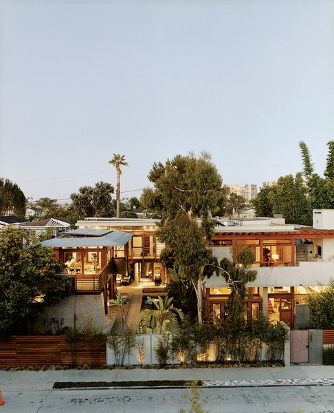 Sustainability in Stages - Photo 6 of 6 - The exuberant results of Hertz’s design are visible from the street. Giant birds <br><br>of paradise, king palms, and bamboo tower above the fence. The Balinese long building, seen on the far left, is almost nautical; on the right, the original house’s rammed-earth entry wall frames its concrete layers.