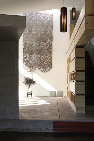 A curtain made of cut sheet steel by Chicago sculptor Mary Brogger hangs in the living room. The knotty-pine bookshelves were designed by Robertson and Ripple Design. The stacked plywood boxes and powder-coated steel spacers allow light to pass through the shelves. On the left is a fireplace faced in the same hand-troweled concrete as the façade; owner Jan Horn likens it to a miniature house. “I love that little building,” he says. Photo 3 of Courtyard House modern home