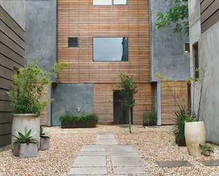 Weathered wood tempers the gray stucco siding and provides a pleasant refuge in the community garden space. 